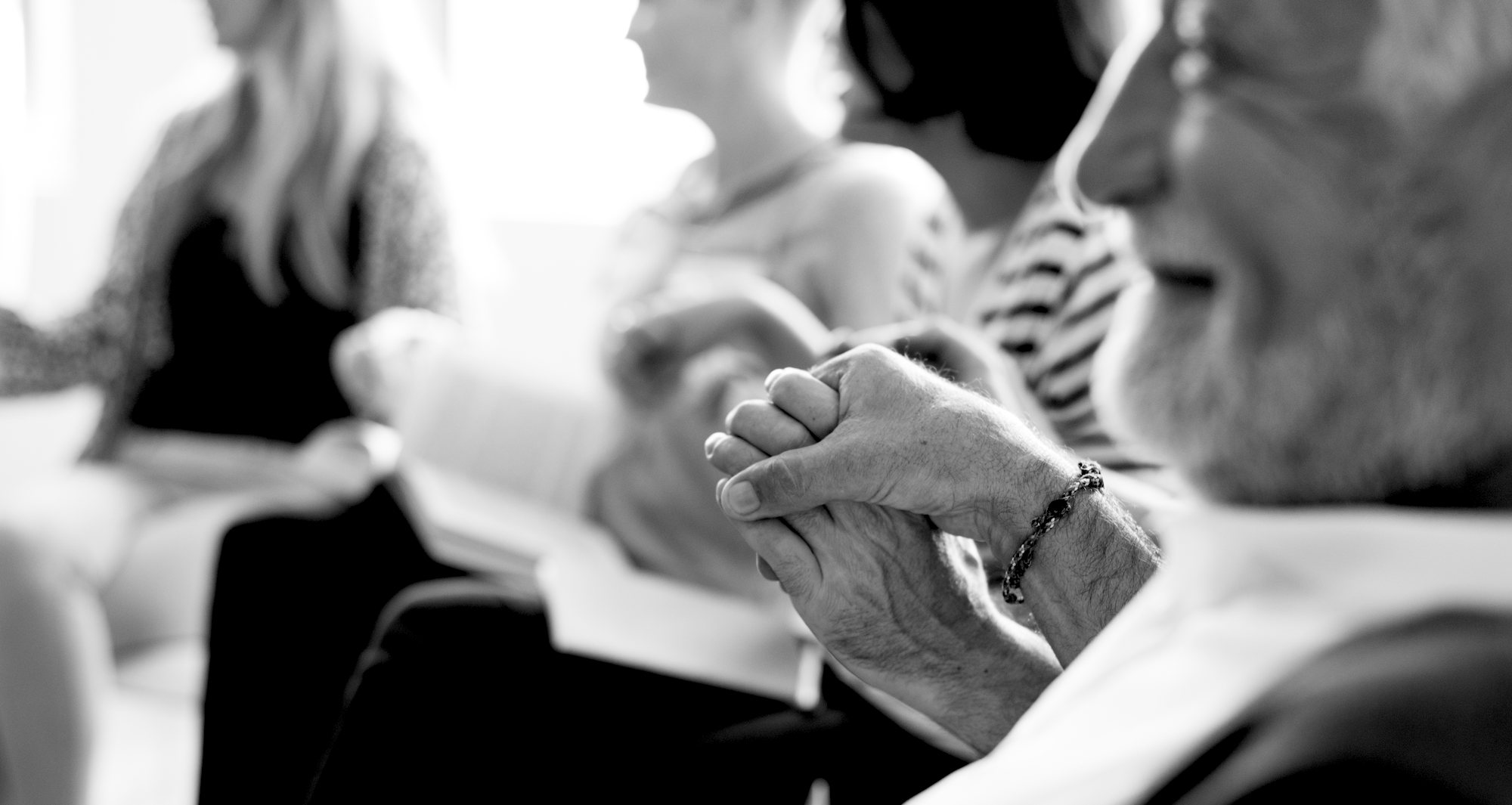 Two older people hold hands in black and white image.