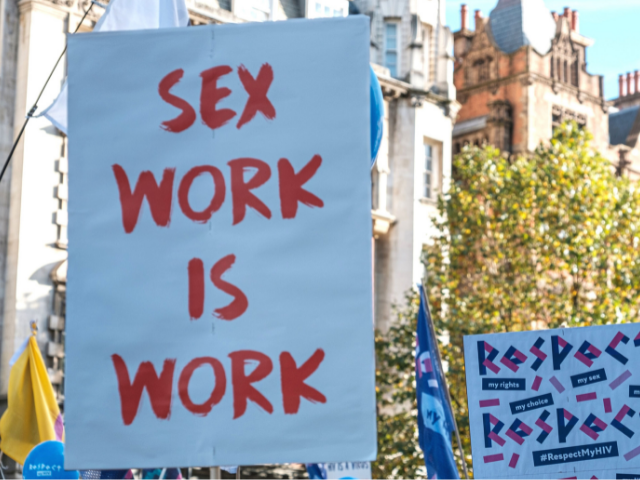 A protest sign with red writing on it that says 'Sex work is work'.