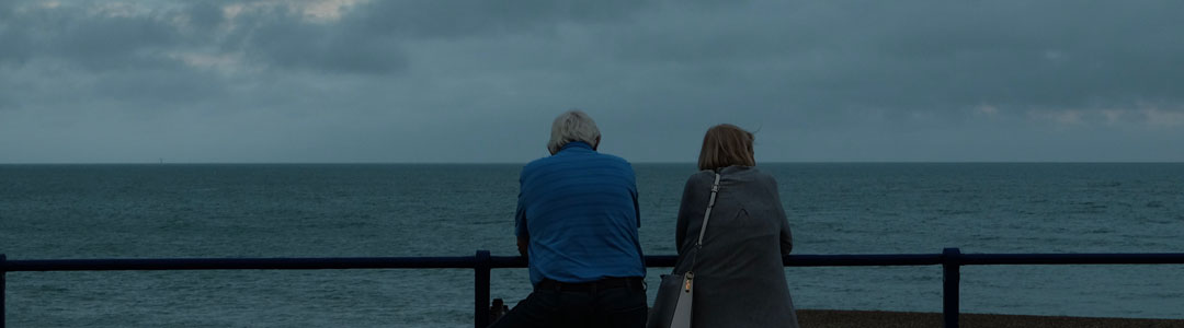 Two people looking out to sea on a grey day.