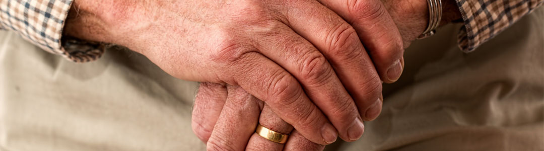 Close up of an older person's hands. They are wearing a thick gold band.