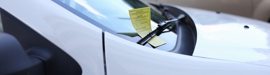 A parking fine on the front windscreen of a car.