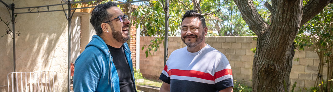 Two men smiling in a garden together.