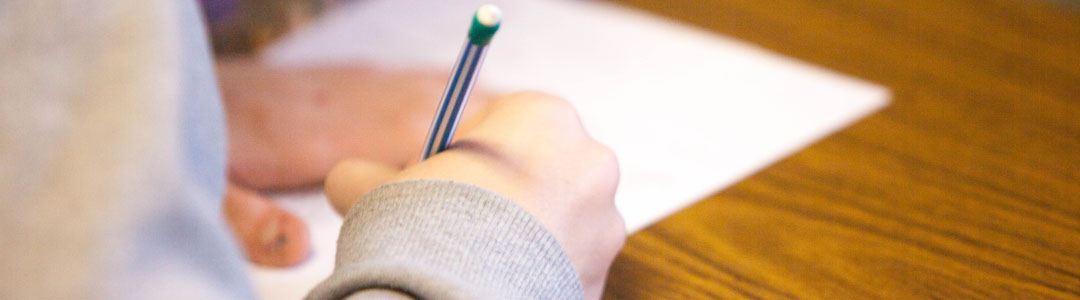 A young person writing on a workbook. 