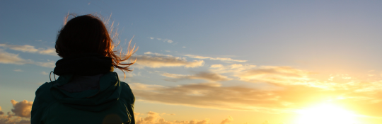 A woman looking out onto a sunset