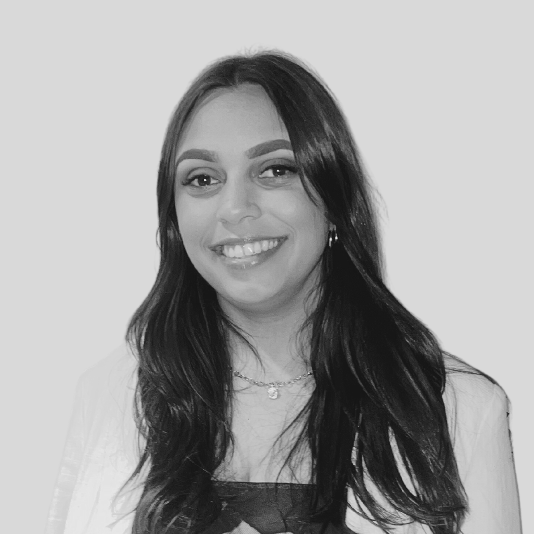 Headshot of Keely smiling, wearing a blazer and long hair.