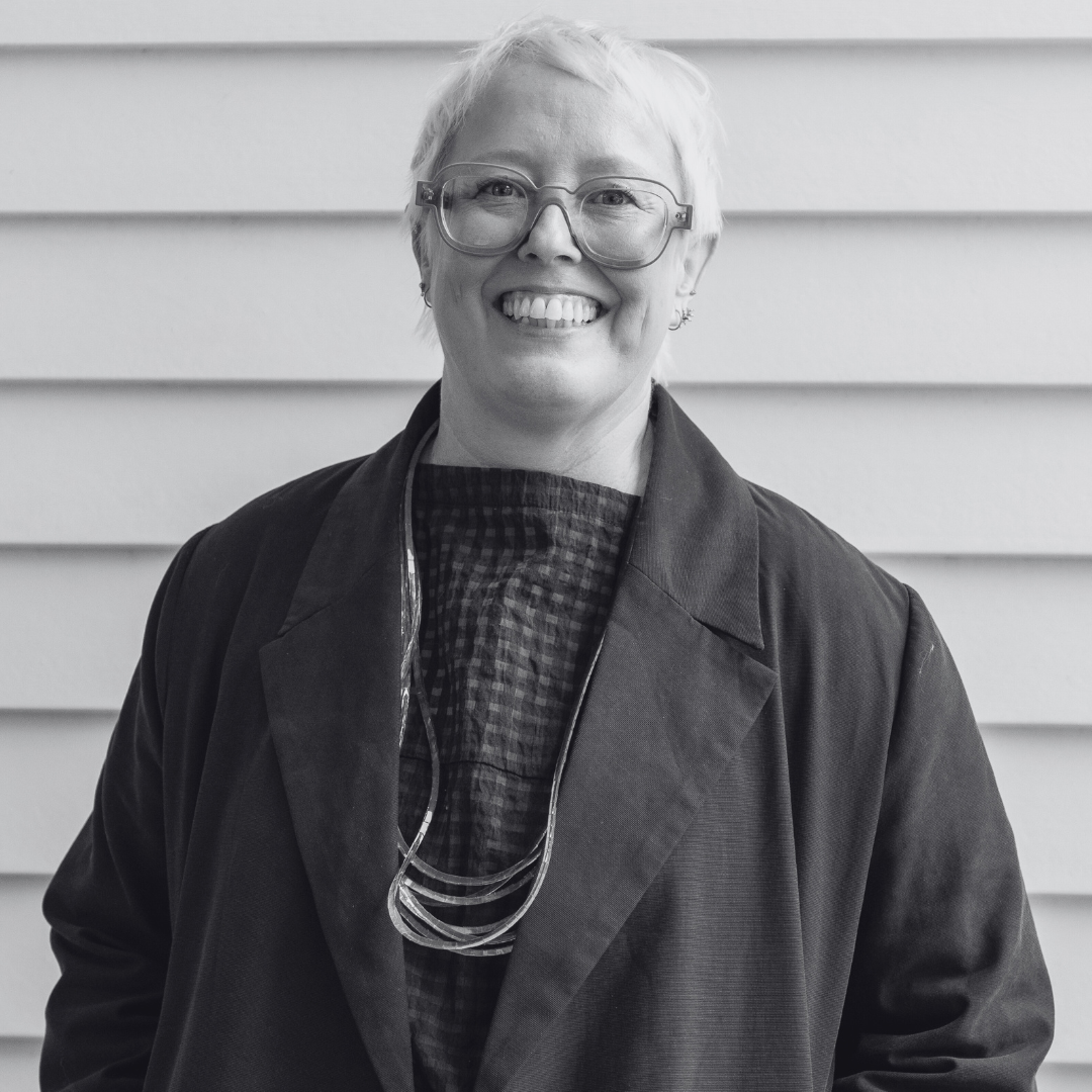 Headshot of Sarah Marland smiling. She has short, blond hair and is wearing thick-rimmed glasses.