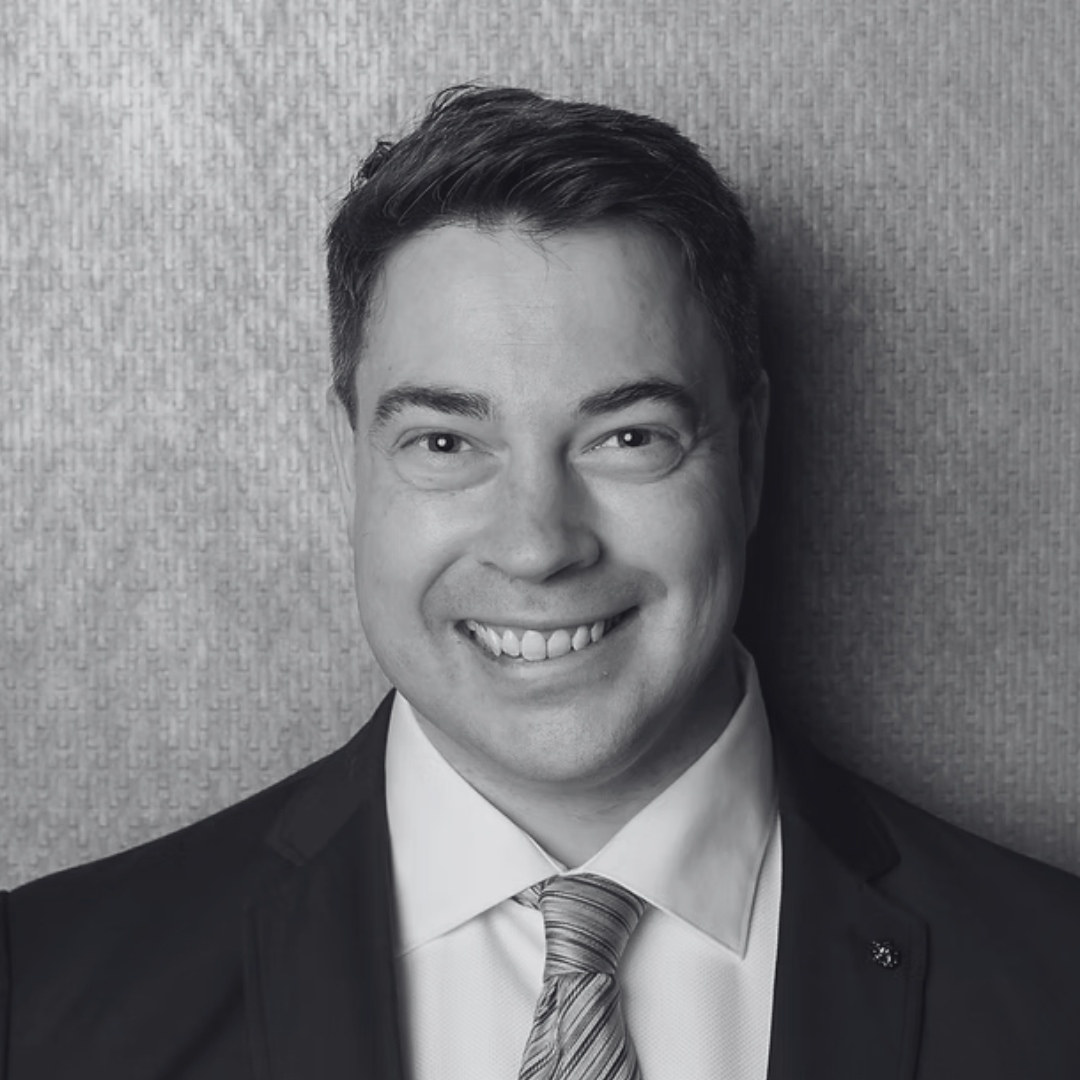 Headshot of Mark Holden smiling at the camera. He has short hair and wears a blazer, shirt and tie.
