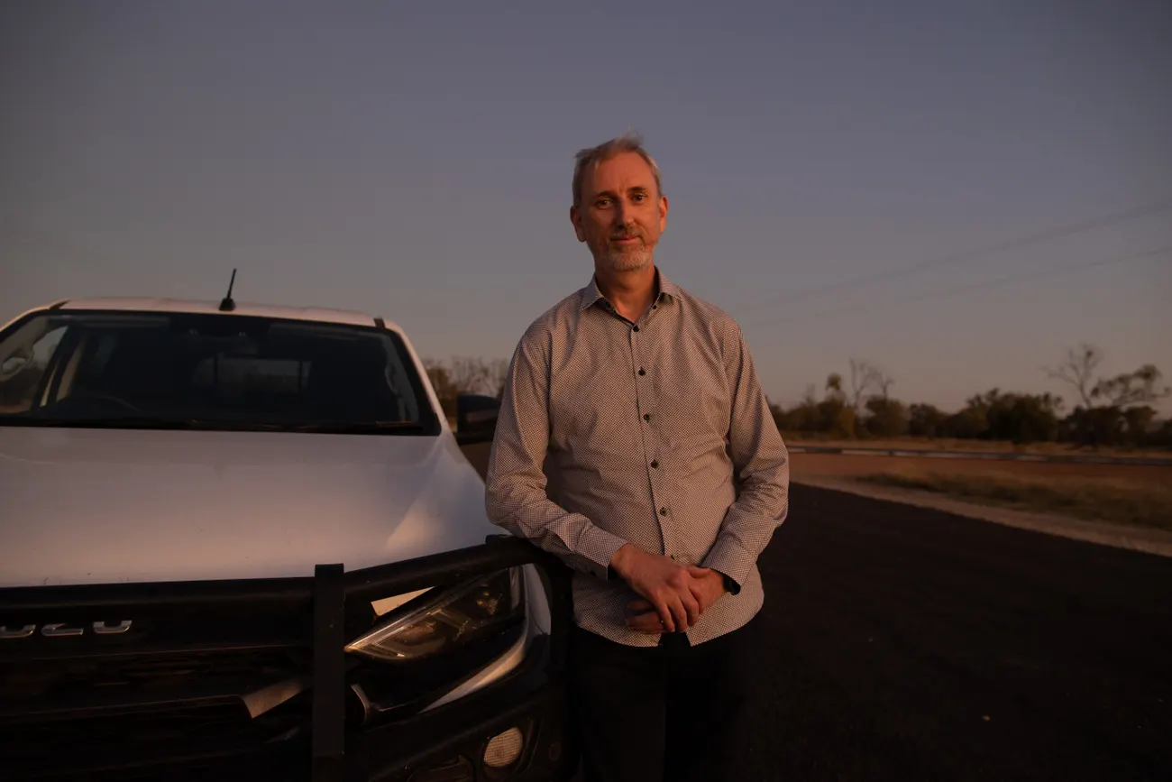 A man standing next to a ute at sunset. 