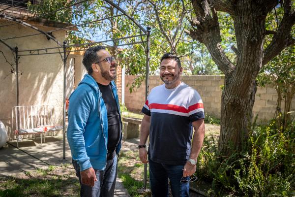 A man living with HIV laughing with a friend in a garden.