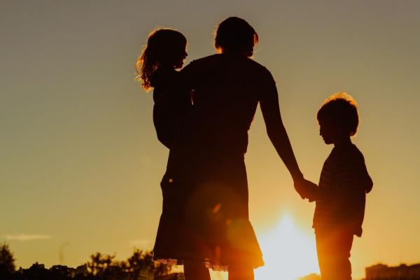 Silhouette of a woman and two children at sunset.